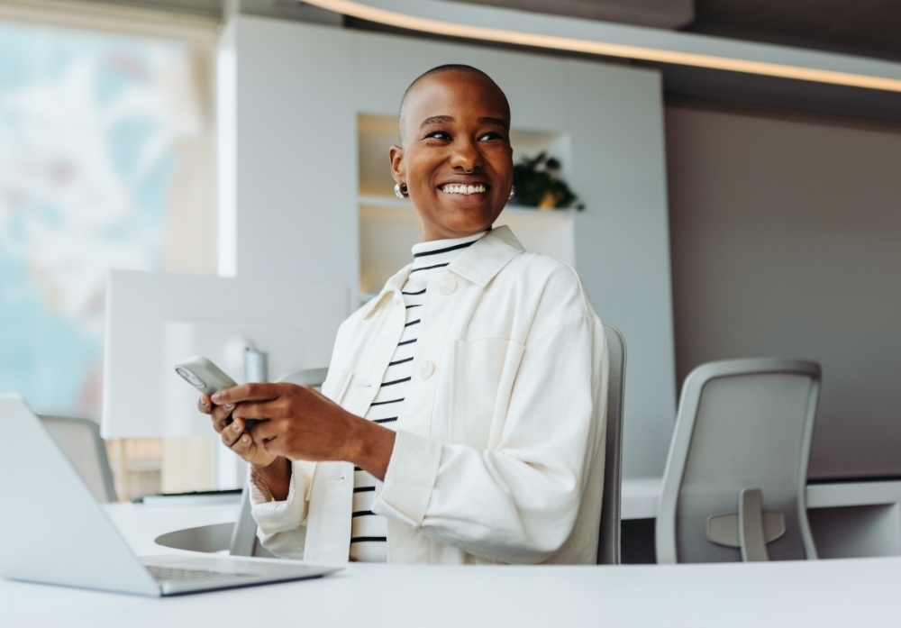 a woman smiling holding a mobile in the office