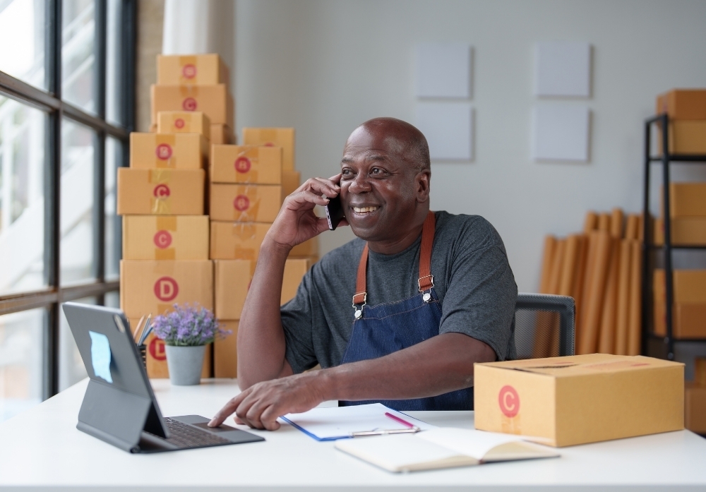 a man in the phone in an office with delivery boxes 