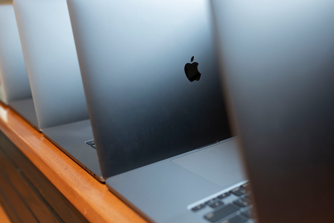 MacBooks open in a row on a table