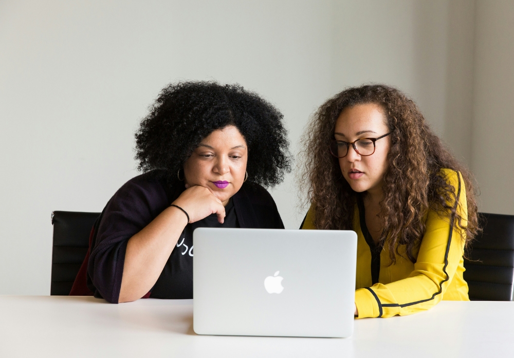 Two women focused working together while using MacBook