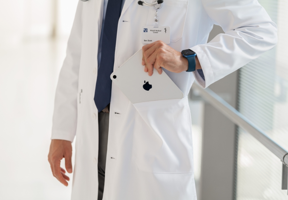 Doctor holding an iPad in his white coat while wearing an apple watch