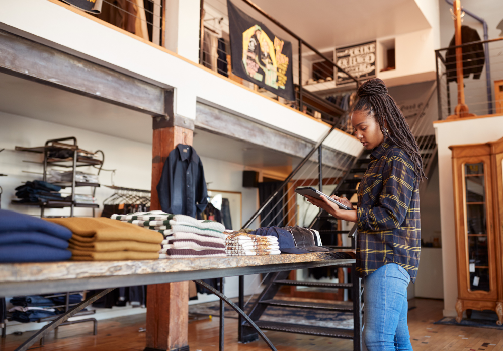 Female Owner Of Fashion Store Using Digital Tablet To Check Stock In Clothing Store